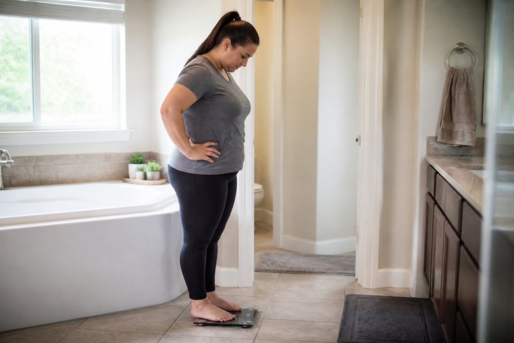 Person in their 40s checking a digital scale, reflecting on progress during their GLP-1 weight loss journey.