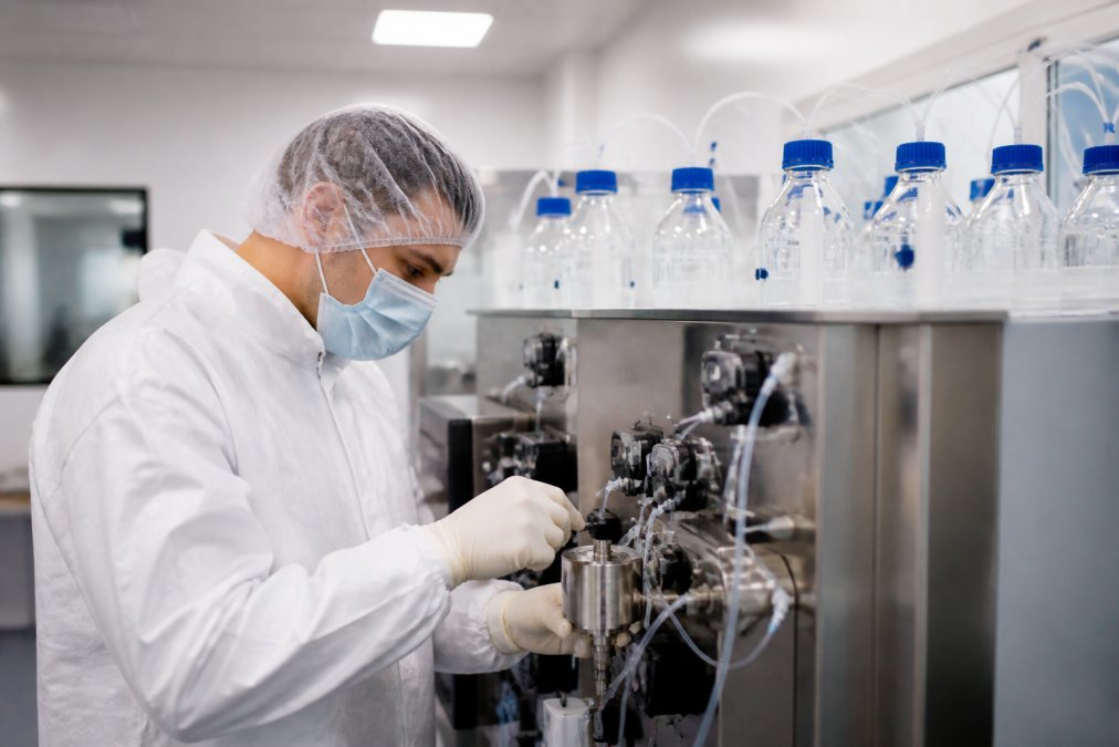 Scientist operating a peptide synthesizer during GMP peptide synthesis in a sterile cleanroom environment