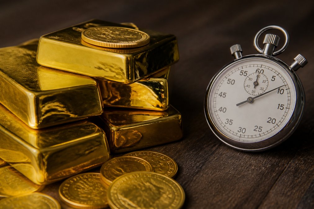 Close-up of gold bullion bars and coins stacked together with warm lighting, emphasizing tangible physical form and intrinsic weight