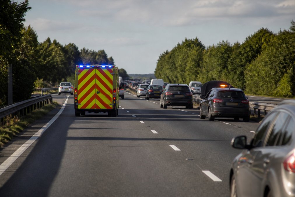 GPS-Enabled Hazard Lights: Why Choose Them Emergency service vehicle responding to a motorway incident with hazard lights visible on a stationary car ahead, demonstrating rapid response scenario with multiple lanes of traffic and daylight conditions