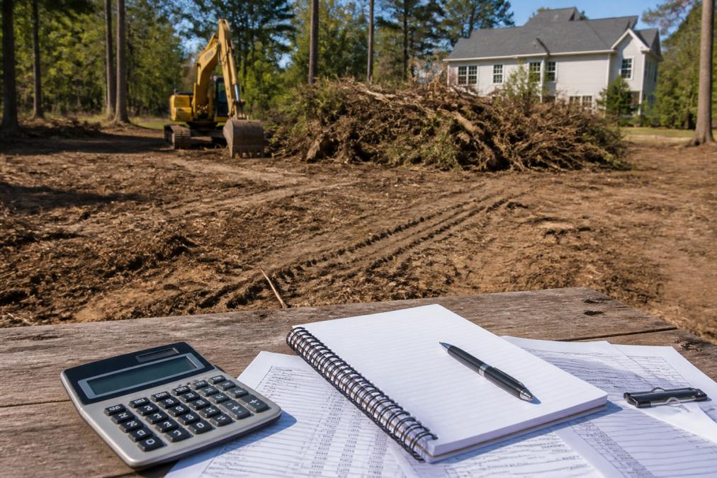 Professional equipment clearing dense vegetation and brush from a residential property, with piled debris visible and freshly exposed soil