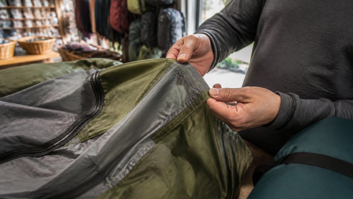 Hands inspecting tent seams and fabric quality to compare Great Outdoor Store vs KingCamp gear durability.