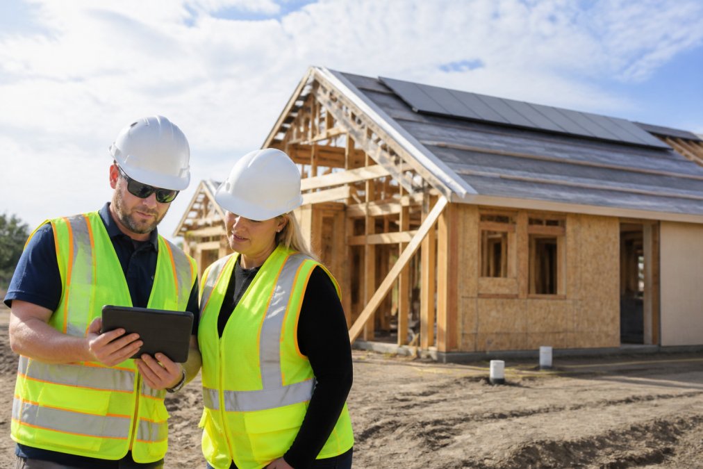 Two consultants reviewing site plans for green energy consulting on a solar-ready residential construction site