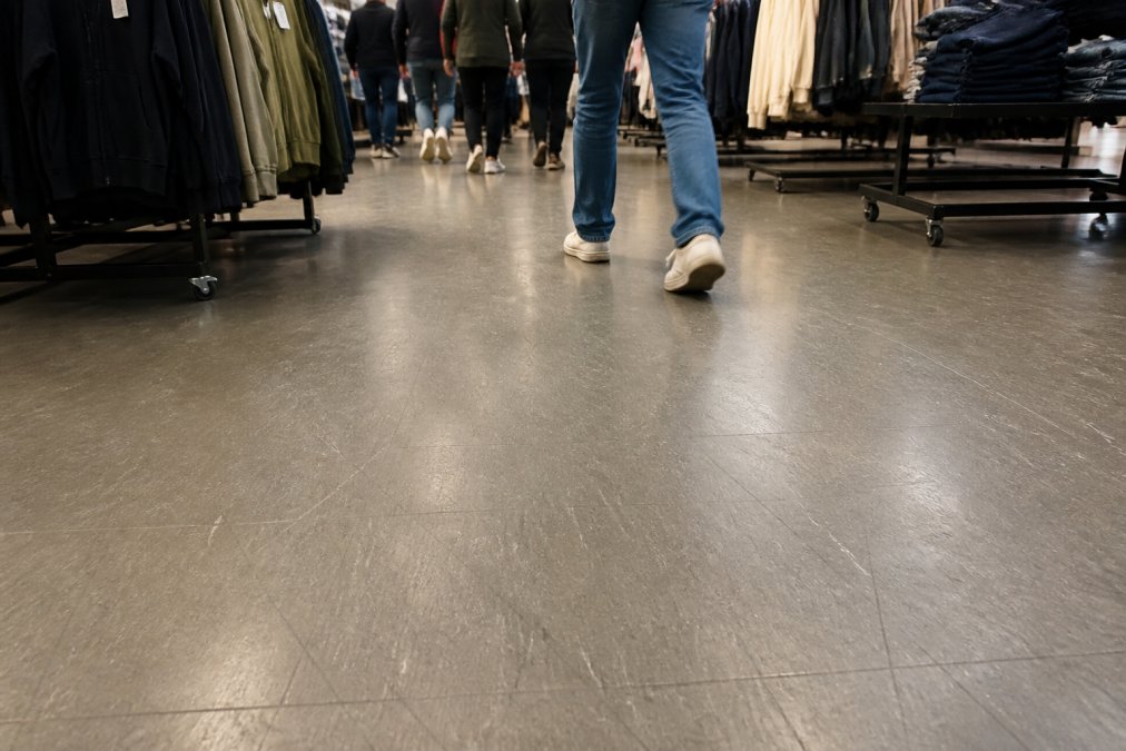 Guide til valg af erhvervsgulv: Alt hvad du skal vide 2 Butiksgulv med synlig slitage fra høj trafik, der viser ridser og mathed fra daglig brug, samt mennesker der går på det slidte gulv