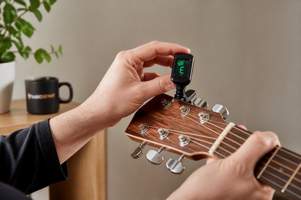 Step-by-step diagram showing how to attach a clip-on tuner to an acoustic guitar headstock for precise guitar tuning.