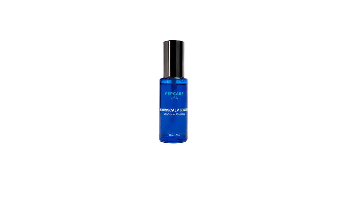 Close-up of hands parting hair to apply copper peptide serum directly onto the scalp with a dropper, soft natural lighting in a bathroom setting