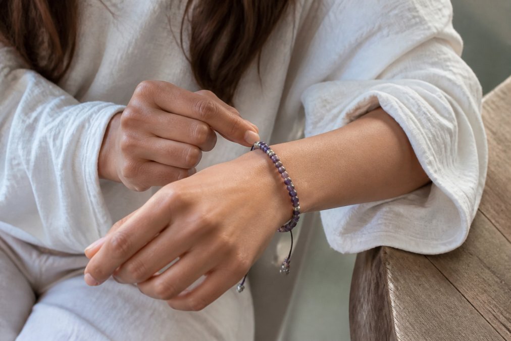Close-up van een vrouw die een handgemaakte verstelbare edelsteen armband om haar pols doet, met natuurlijk daglicht dat de kleuren van de kralen laat zien