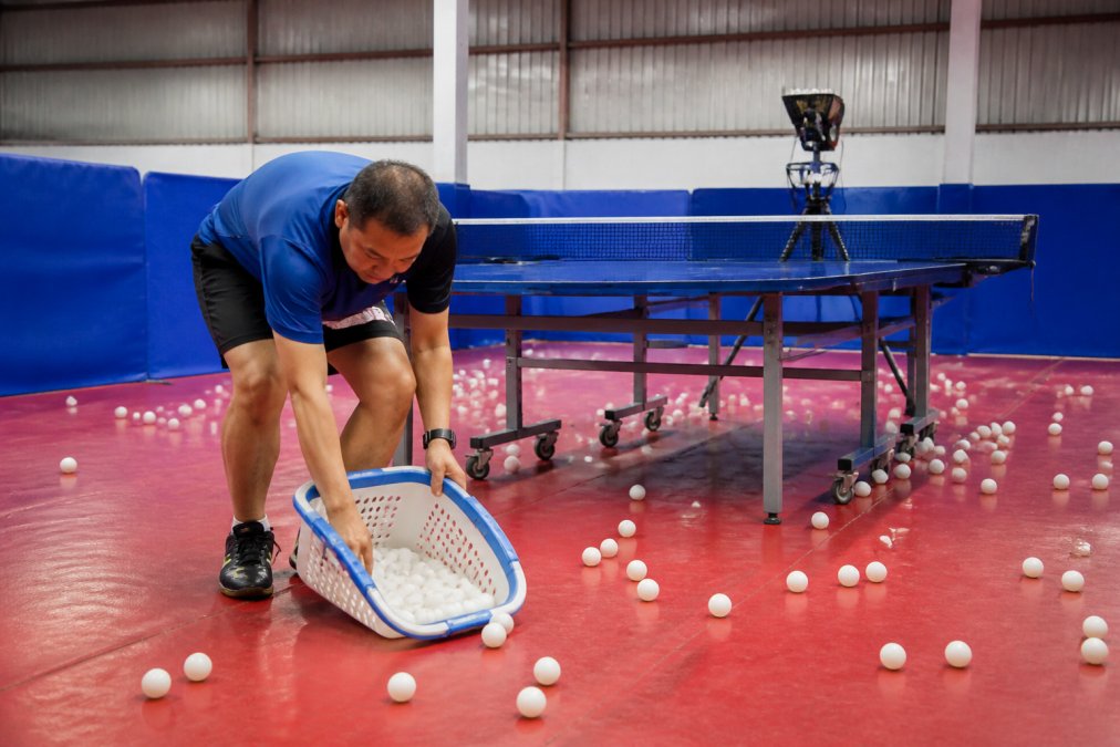 Process diagram comparing manual ball collection to mass produced training aids for efficient table tennis practice