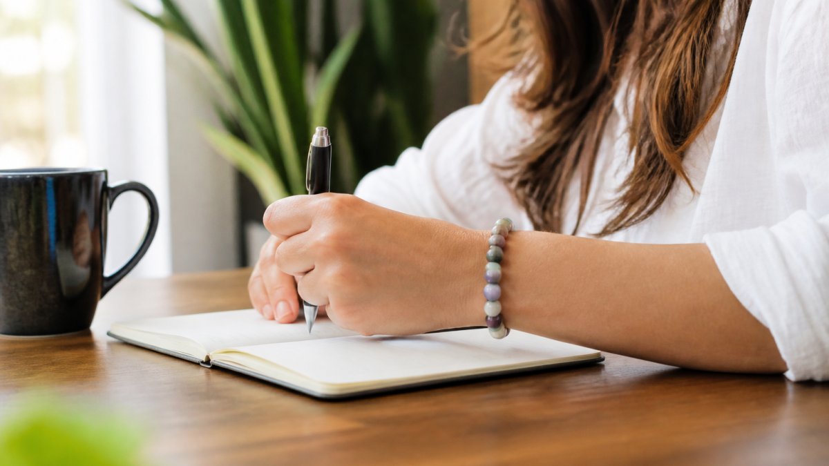 Woman's wrist wearing a colorful beaded crystal bracelet during everyday activity, with natural light highlighting the stone details and comfortable fit on the wrist