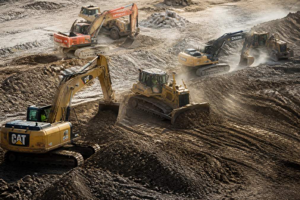 Excavators and bulldozers from various brands working on a site during heavy equipment financing options evaluation