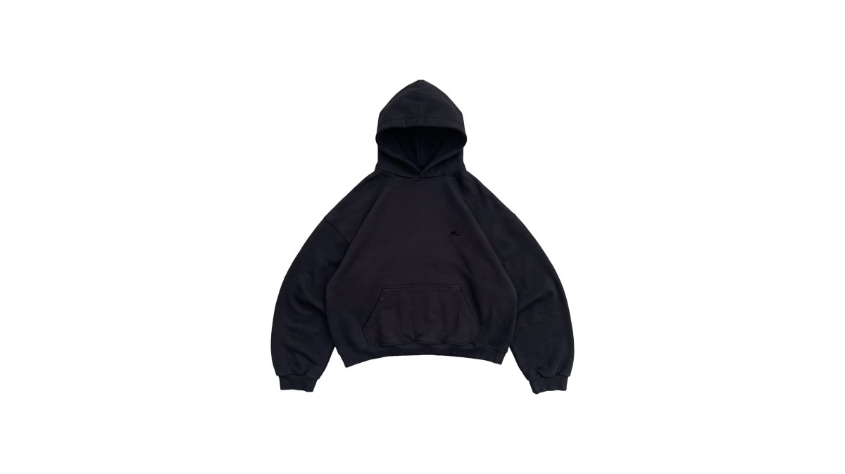 Close-up of a person's hands feeling the thick, dense fabric of a black heavyweight hoodie, showing the brushed inner fleece texture against natural daylight