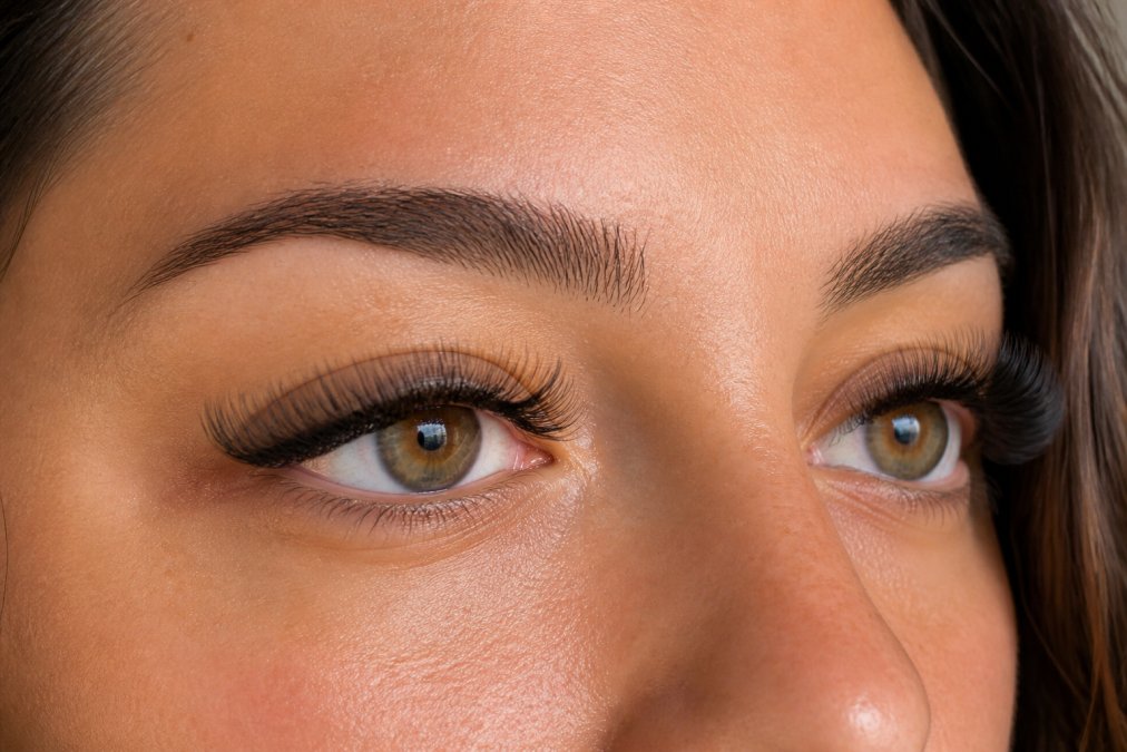 Close-up of a woman's eyes with full lash extensions, showing the detail and fullness of different lash styles in natural lighting