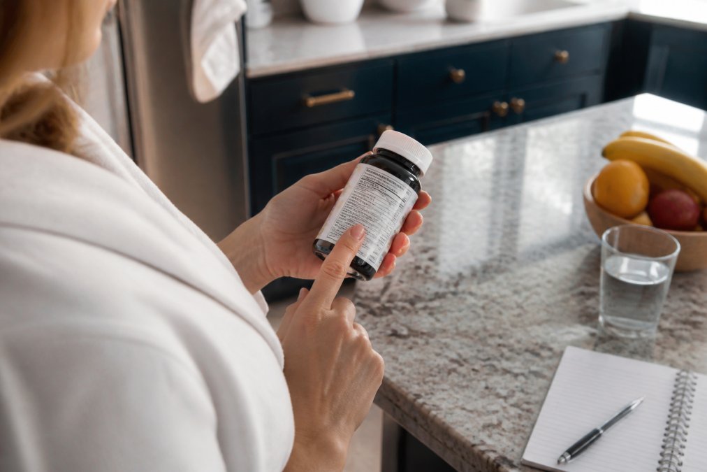 Parent reading the nutrition label on a bottle of hidden sugar children's vitamins in a sunny kitchen