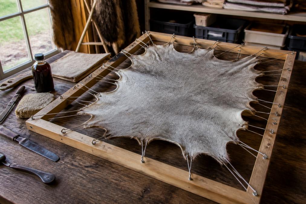Crafter stretching a tanned hide on a wooden frame as one of the best fur alternatives for DIY projects