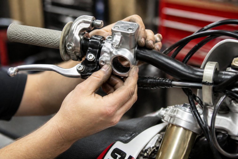 Mechanic installing a precision master cylinder for motocross brake upgrades on a bike handlebar
