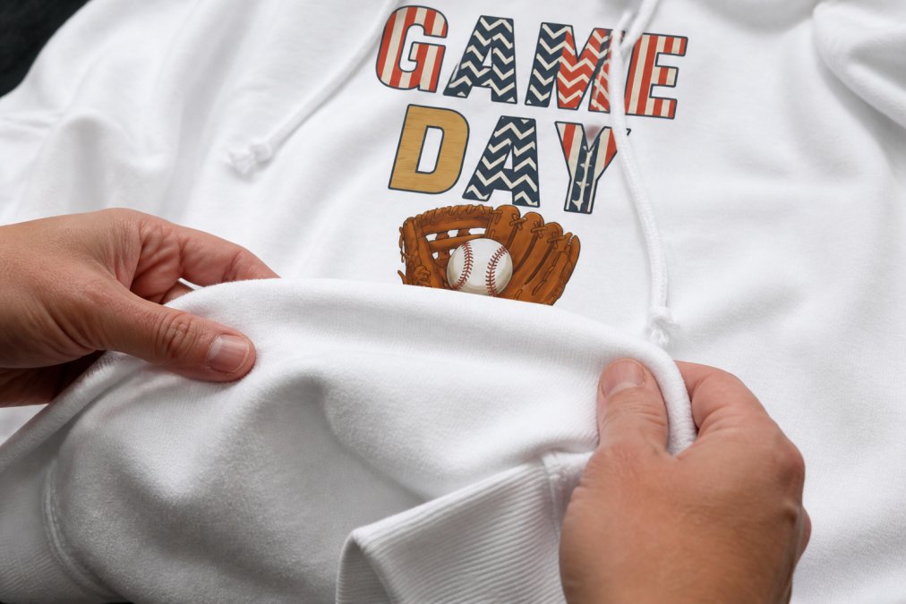 Close-up of hands examining soft cotton-polyester blend fabric texture on custom team apparel, showing moisture-wicking weave and durability under natural lighting