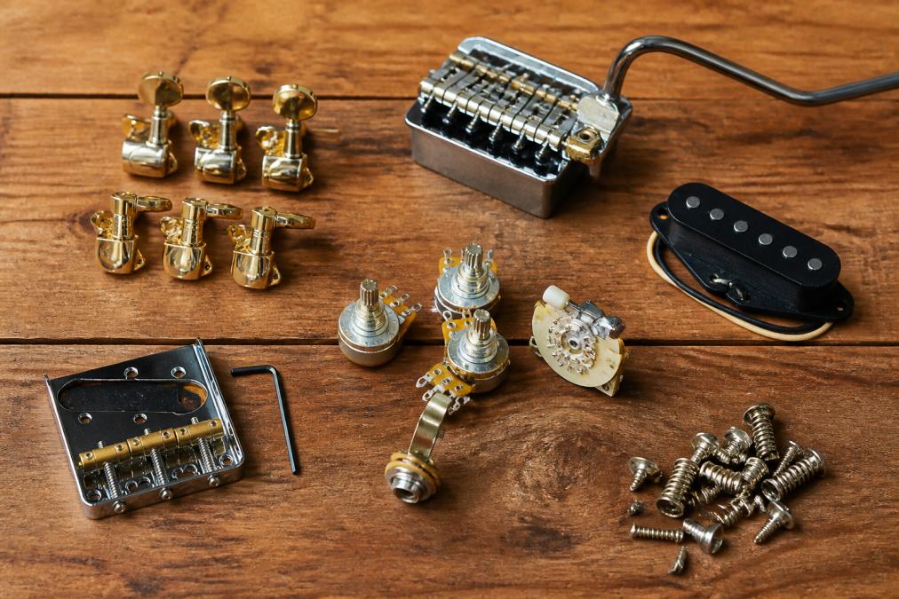 Flat lay of various guitar hardware components including bridge, machine heads, potentiometers, and pickup arranged on a wooden surface with natural lighting