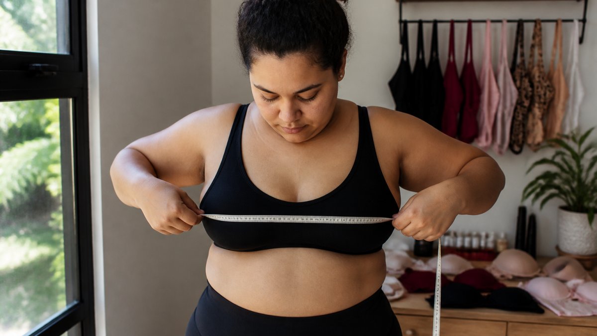 Woman measuring her underbust with a tape to find the right fit for high quality lingerie for curvy bodies.