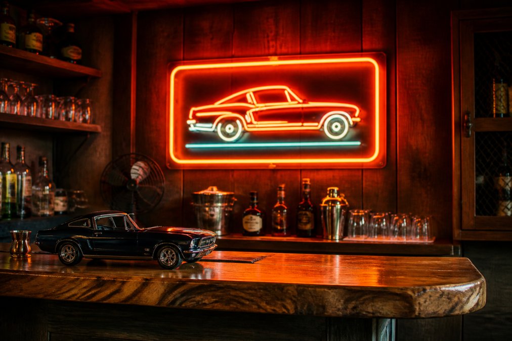 Vintage neon signs glowing above a home bar with retro decor and glassware