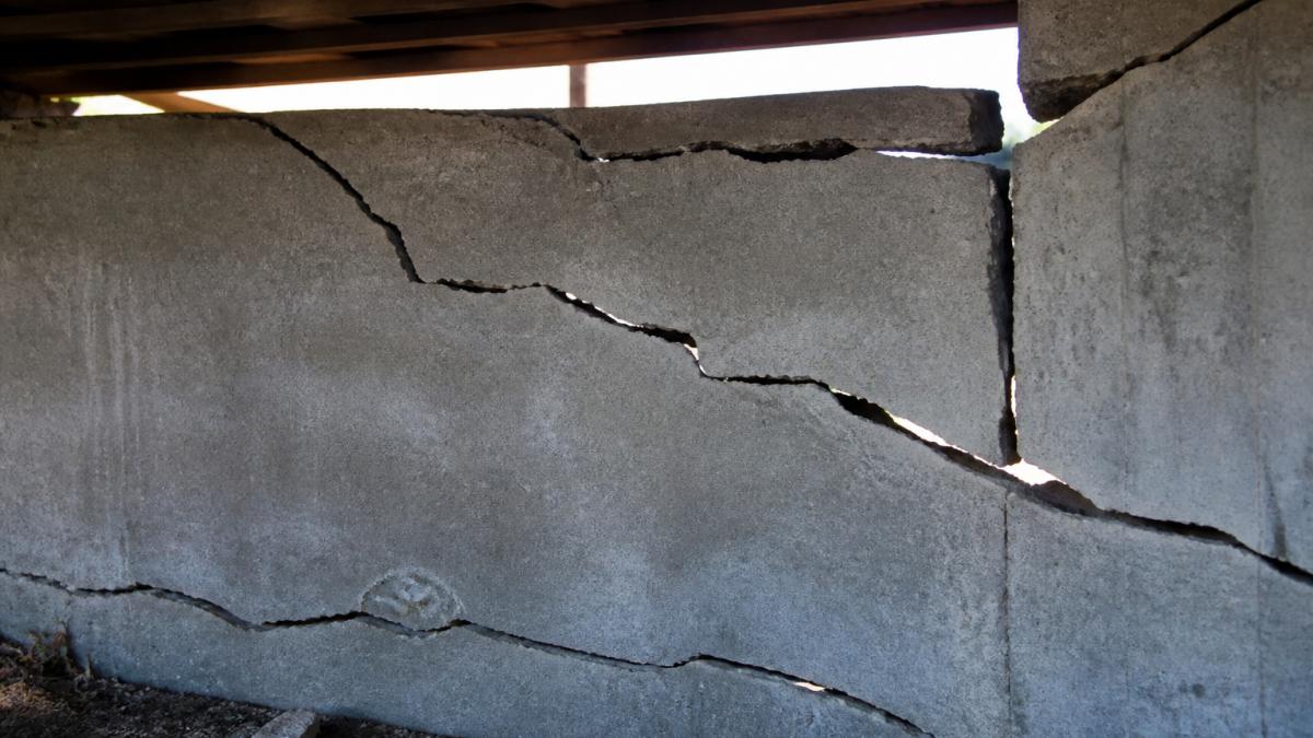 Diagram illustrating hillside home structural damage through concrete foundation cracks and daylight gaps