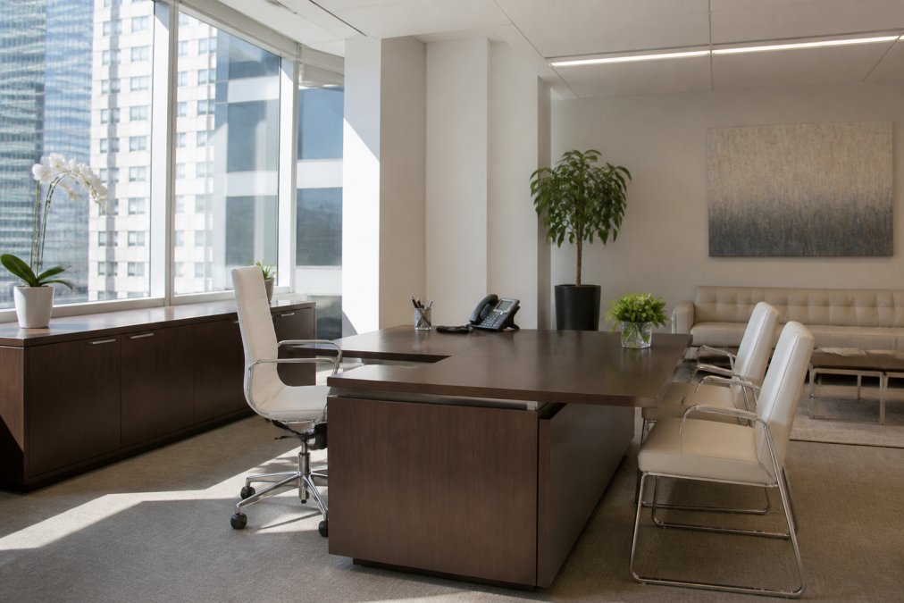 Bright, organized corporate office space with natural window light streaming across clean desks, modern furniture, and neutral wall colors ready for a professional photography session