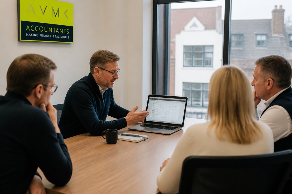 A confident finance professional presenting financial data on a laptop screen to a small group of business owners around a meeting table in a bright modern meeting room