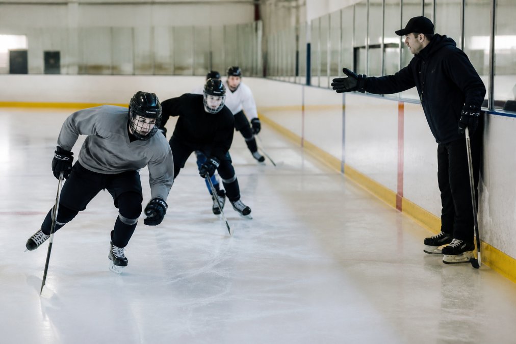 Coach instructing a group during hockey training for recreational players Edmonton on an indoor rink