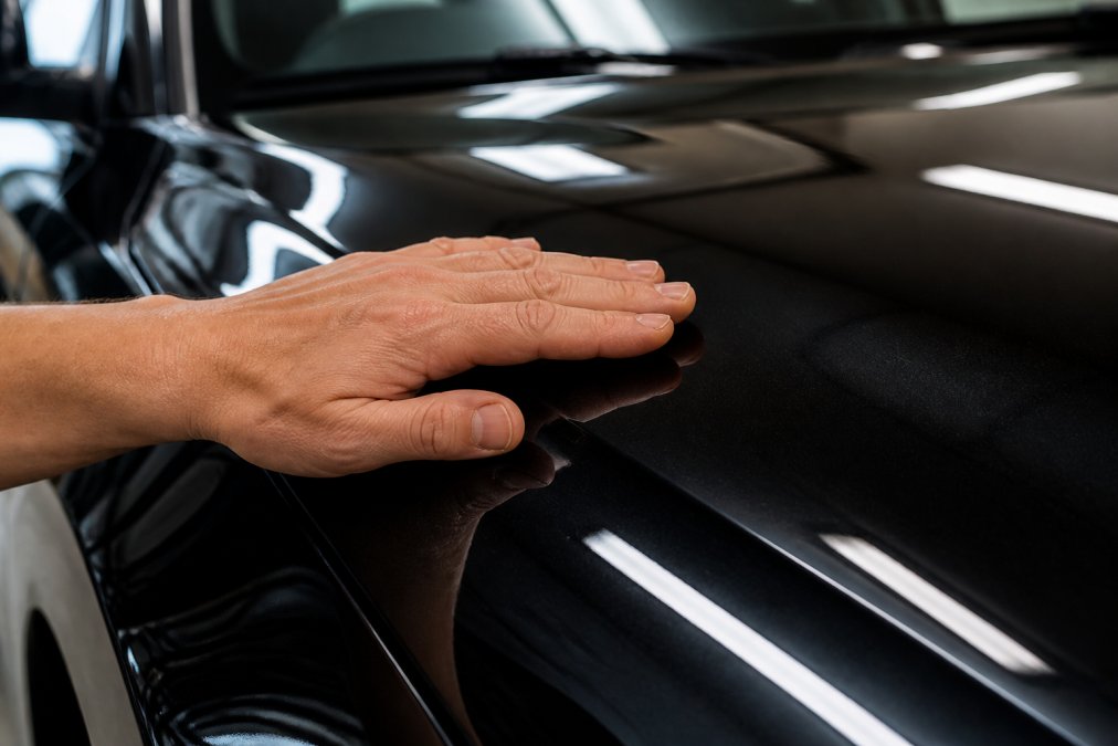 Close-up van verschillende autolakken onder verschillende lichtomstandigheden, met de hand aanrakend een glanzende zwarte laklaag
