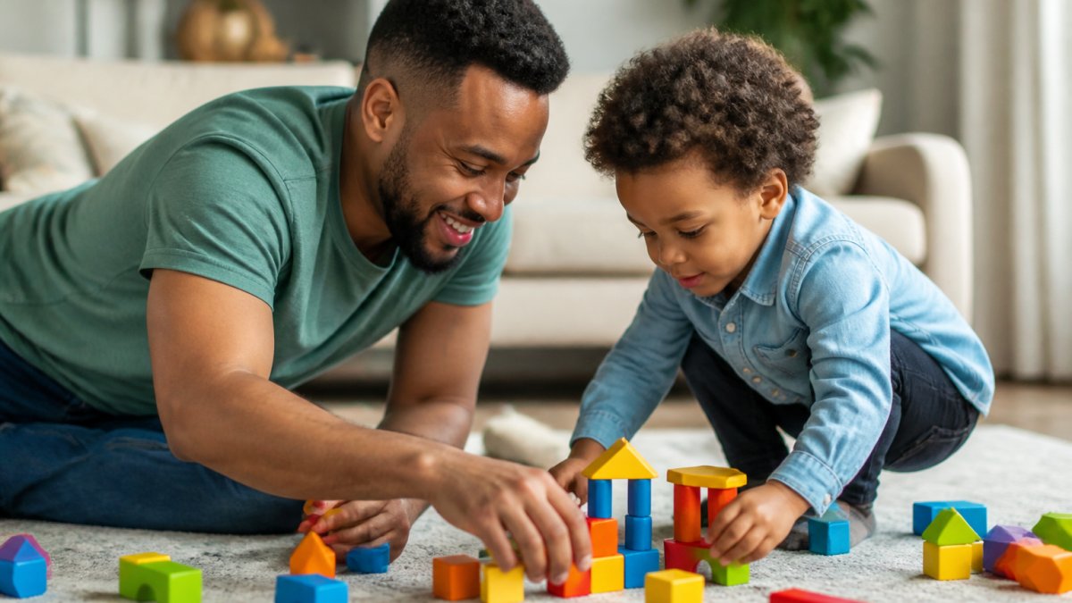 Parent and child engaged in floor-level play together in a comfortable home setting, showing natural interaction and emotional connection during playtime