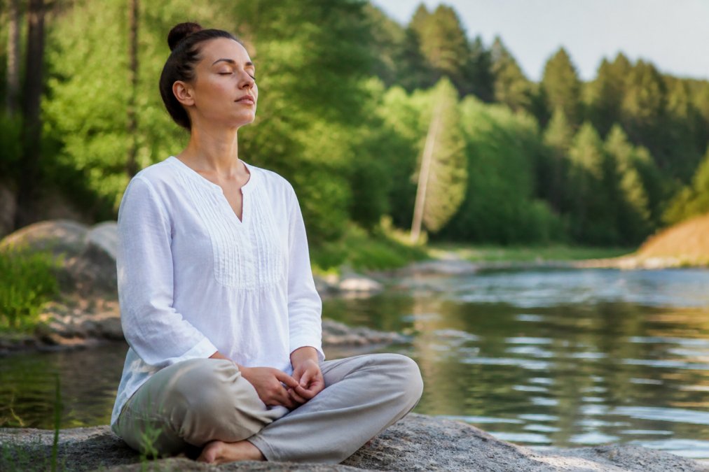 Person sitting peacefully outdoors in natural light with hands resting gently on lap, showing calm posture and relaxed shoulders while practicing breathwork
