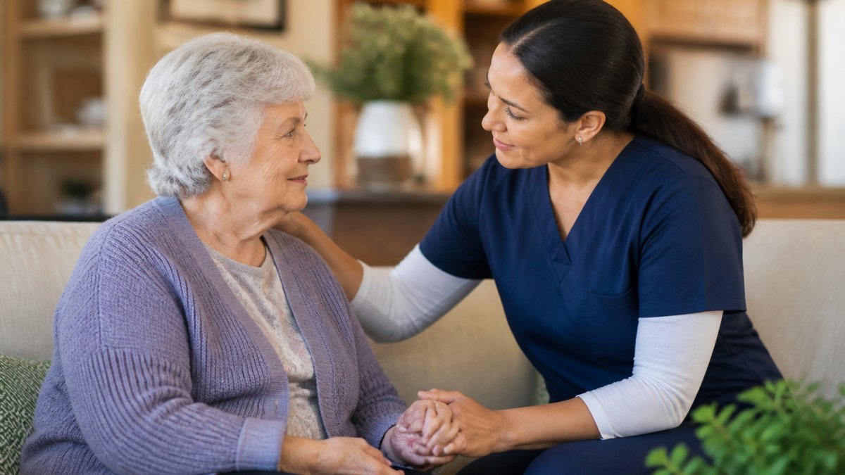 Professional caregiver providing calm, supportive care to senior in comfortable home setting with warm lighting and peaceful expression