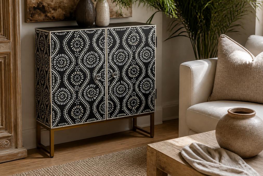 Close-up of a handcrafted bone inlay coffee table surface showing intricate black and white geometric inlay pattern on solid mango wood, styled with a linen throw and ceramic vase in a warmly lit living room