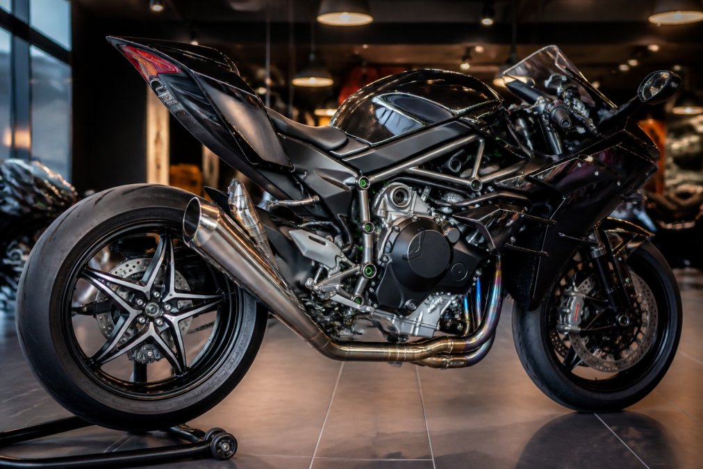 Kawasaki Ninja H2 First Edition in zwart-chroom finish onder showroom-verlichting, detail van de supercharger en titanium uitlaat zichtbaar