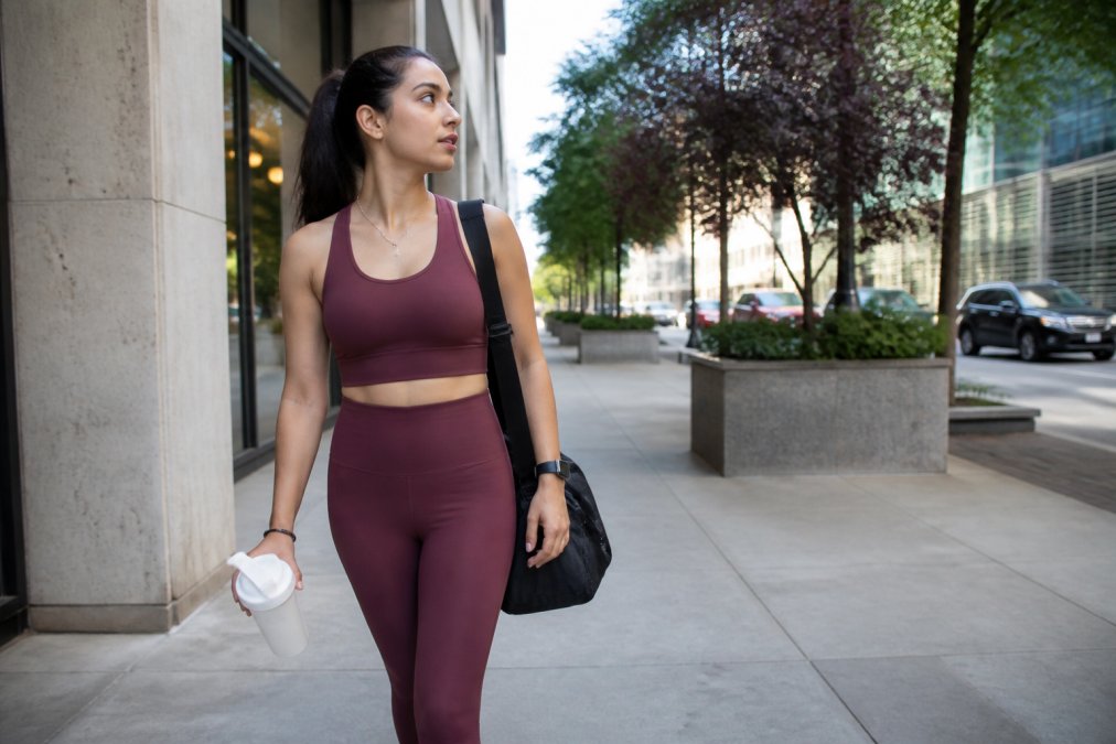 Woman wearing coordinated activewear set transitioning from gym to casual setting, styled with minimal accessories showing how gym clothes work for daily life in urban environment
