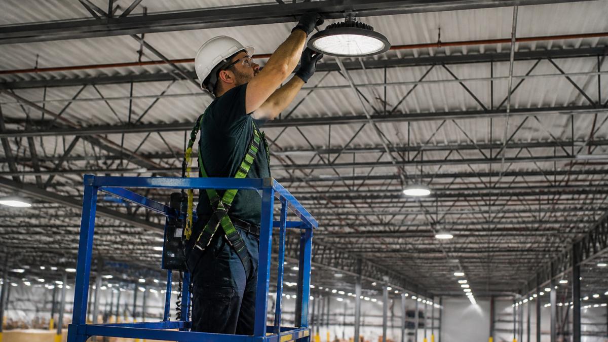 Technician installing warehouse LED lighting for Pearl Street Systems vs Ameresco project quality standards