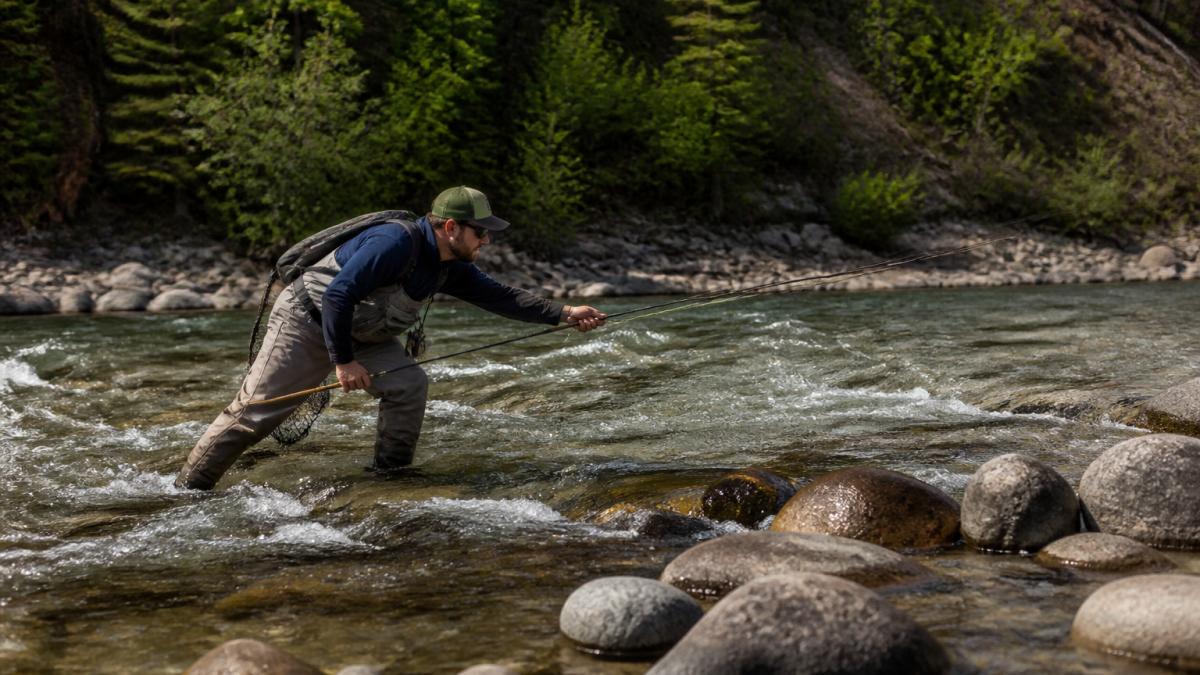 Angler demonstrating safe wading stance in a river to practice fly fishing safety in Alberta.