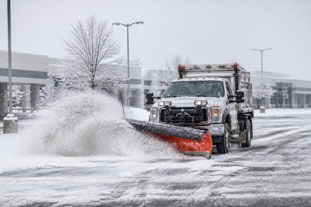 Snowplow clearing a snowy commercial parking lot for winter equipment age financing operations