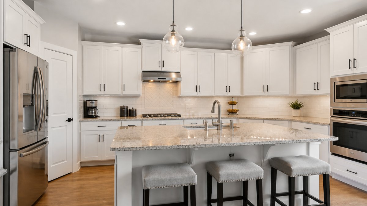 Modern kitchen with updated white cabinetry, granite countertops, stainless steel appliances, and pendant lighting over an island, showing professional renovation quality
