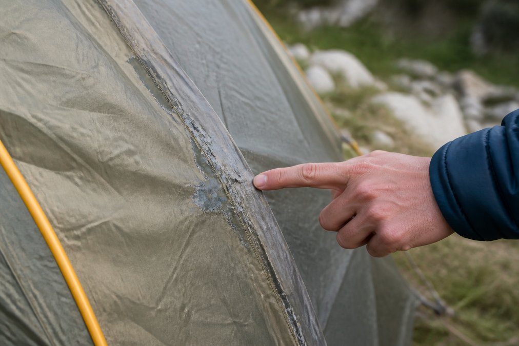 Diagram showing frayed tent stitching and peeling waterproof coating as indicators of gear failure