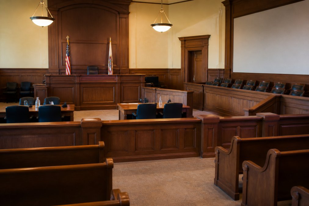 Interior of a courtroom with judge's bench, wooden furniture, empty jury box, and formal legal setting showing where domestic violence cases are heard