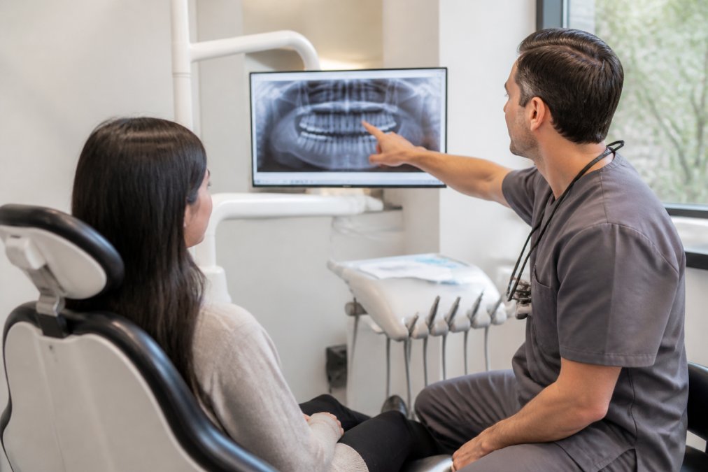 Dentist reviewing dental x-rays with a patient during an emergency dental appointment in a modern office.