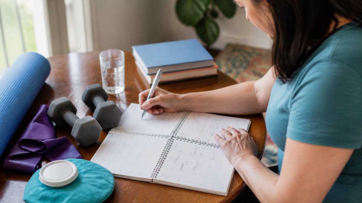 Patient keeping a pain journal with a calendar and pen, tracking daily pain levels and activities at home