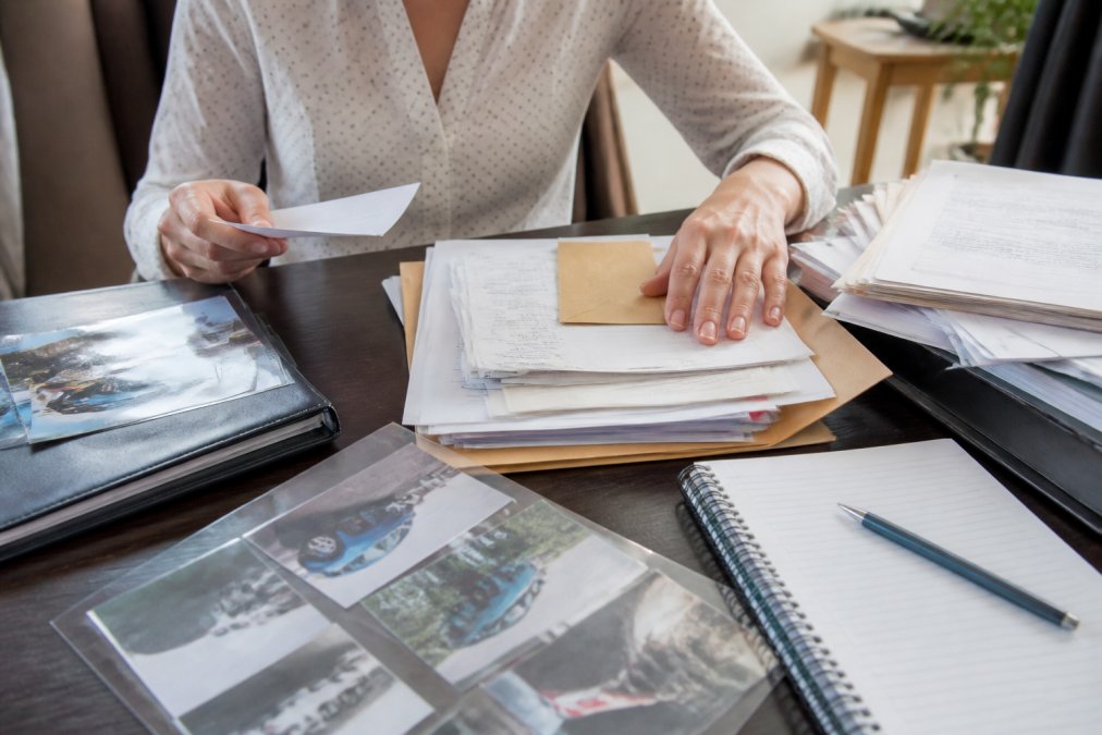 Hands organising medical records and receipts on a desk to help reduce personal injury settlement time through preparation.