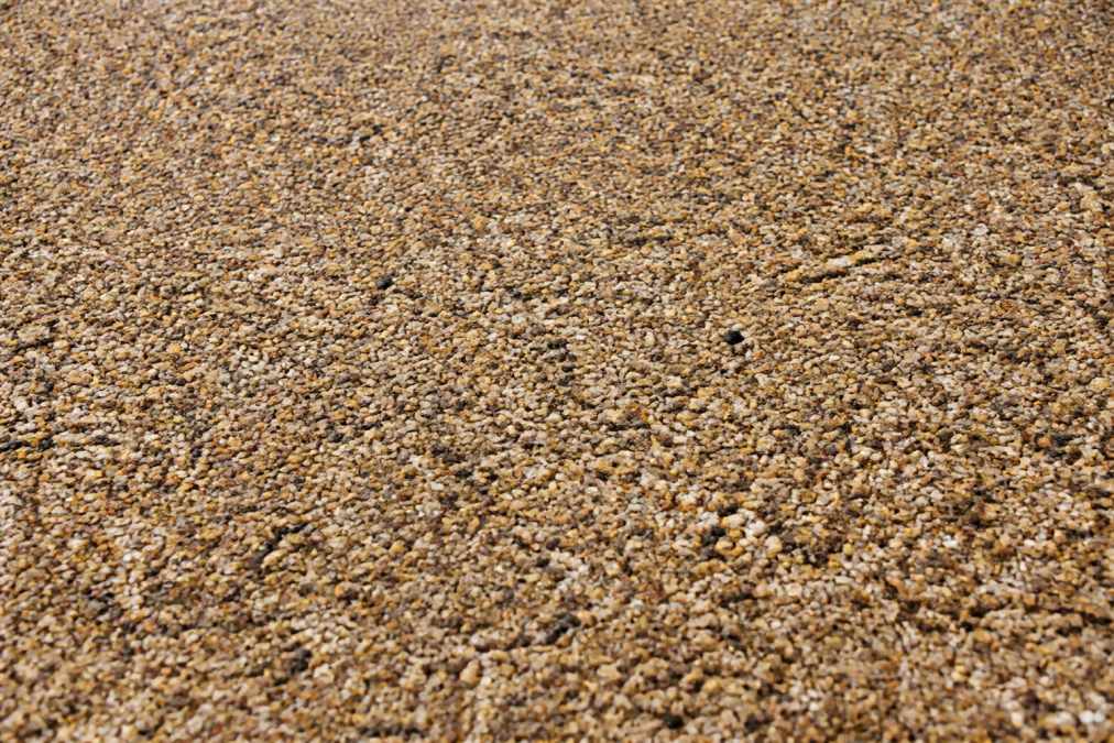 Close-up detail of resin bound driveway surface showing decorative stone aggregate in warm earth tones with subtle colour variation and seamless finish