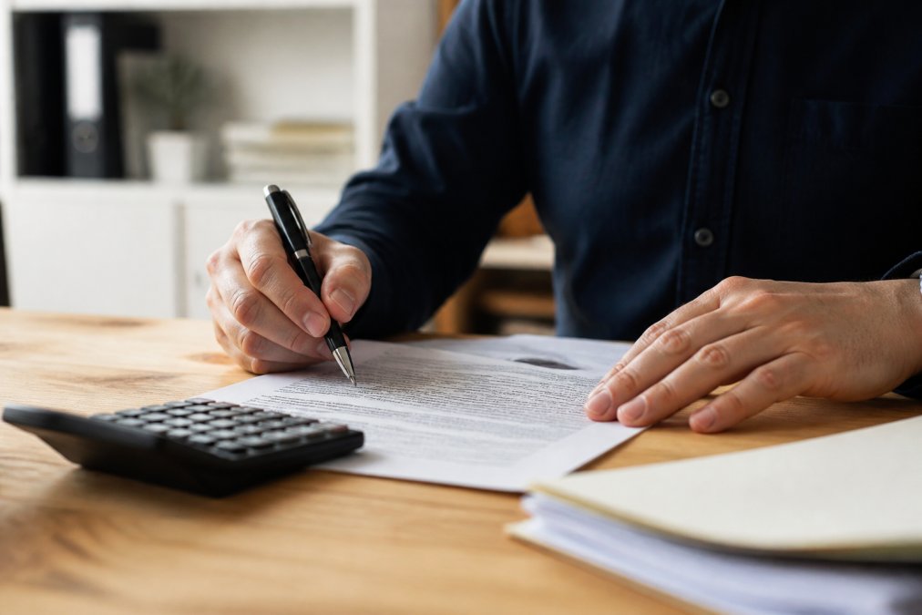 Hands reviewing legal divorce documents and a calculator to divide retirement accounts
