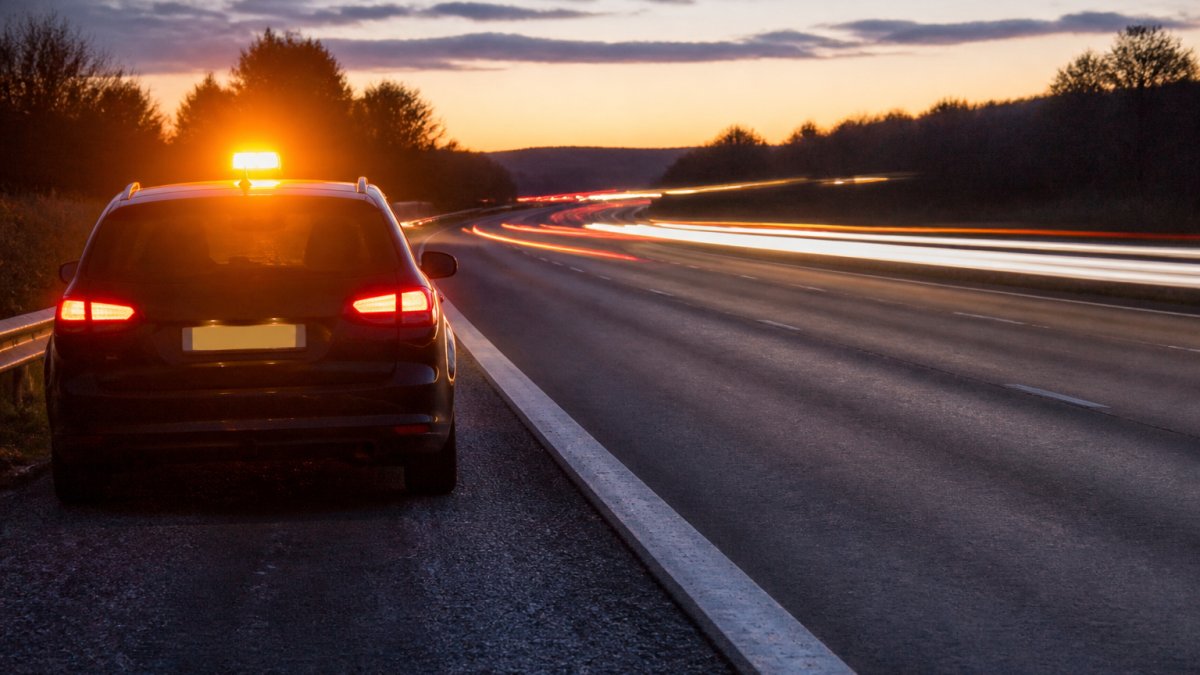 How Smart Hazard Lights Reduce Emergency Response Times Broken-down car on a motorway at dusk using smart hazard lights to remain visible to passing traffic.