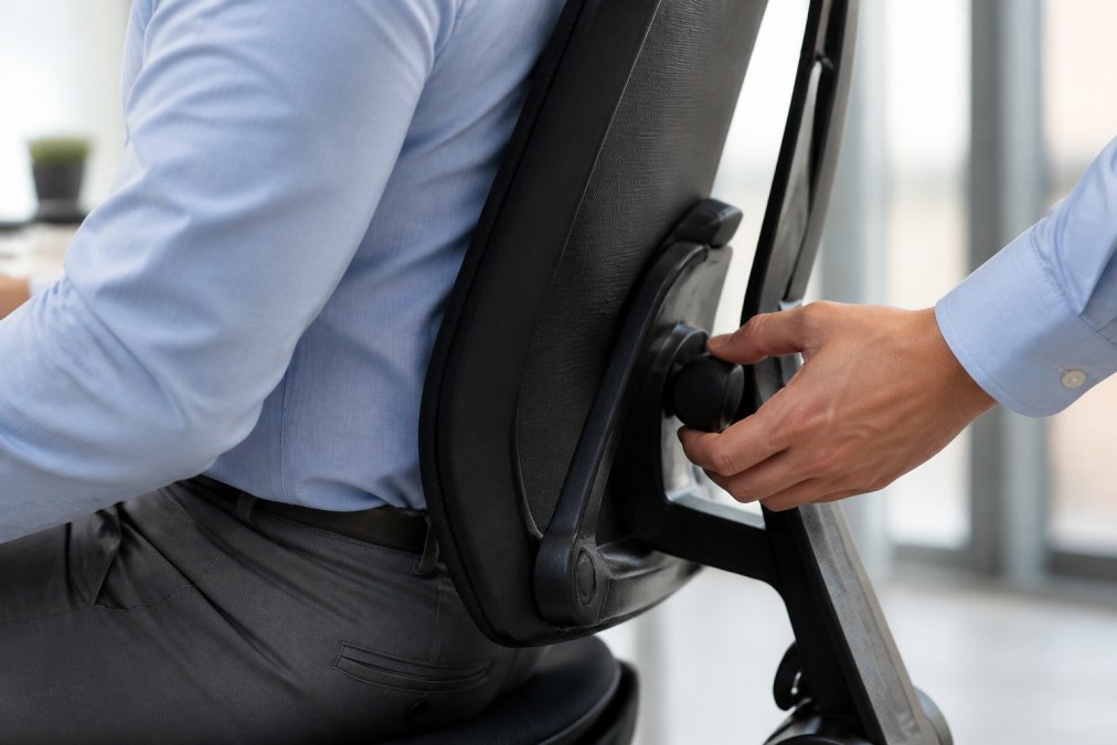 Hand adjusting the lumbar support knob on an ergonomic chair to learn how to adjust office chair for posture