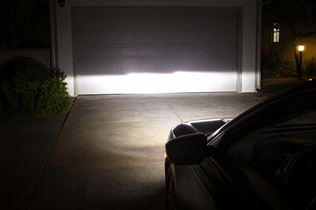 Vehicle parked 25 feet from a garage wall at night, LED headlights illuminated, showing a clean beam pattern and sharp cutoff line on the wall surface with clear light distribution