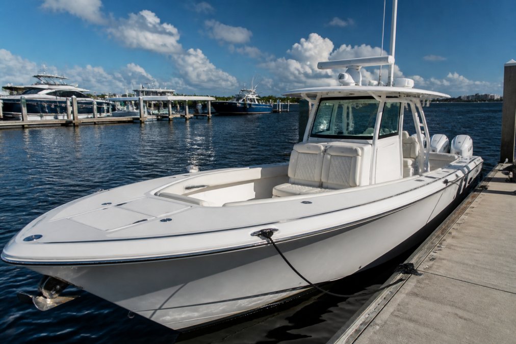Well-maintained center console yacht at dock with gleaming white hull, organized deck equipment, polished stainless steel railings, clean upholstery, and professional detailing under bright daylight