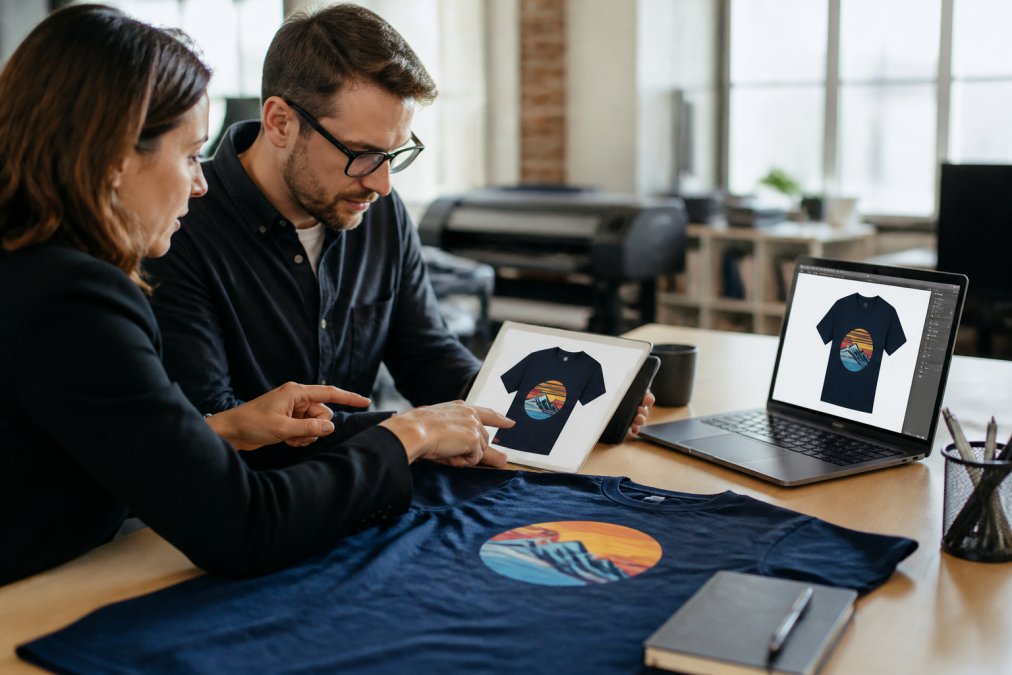 Graphic designer and manager reviewing digital proofs to approve custom mockups of apparel designs